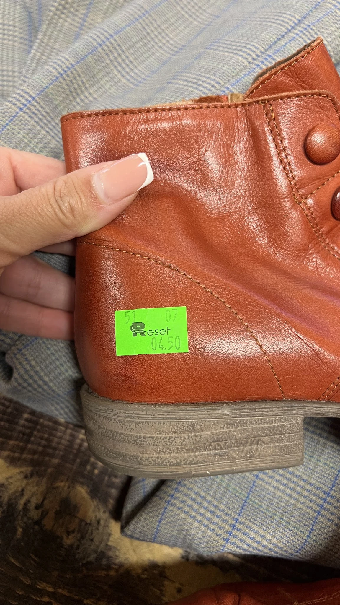 Close-up van een bruinleren schoen met een groen Reset-label