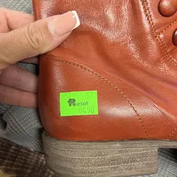 Close-up van een bruinleren schoen met een groen Reset-label
