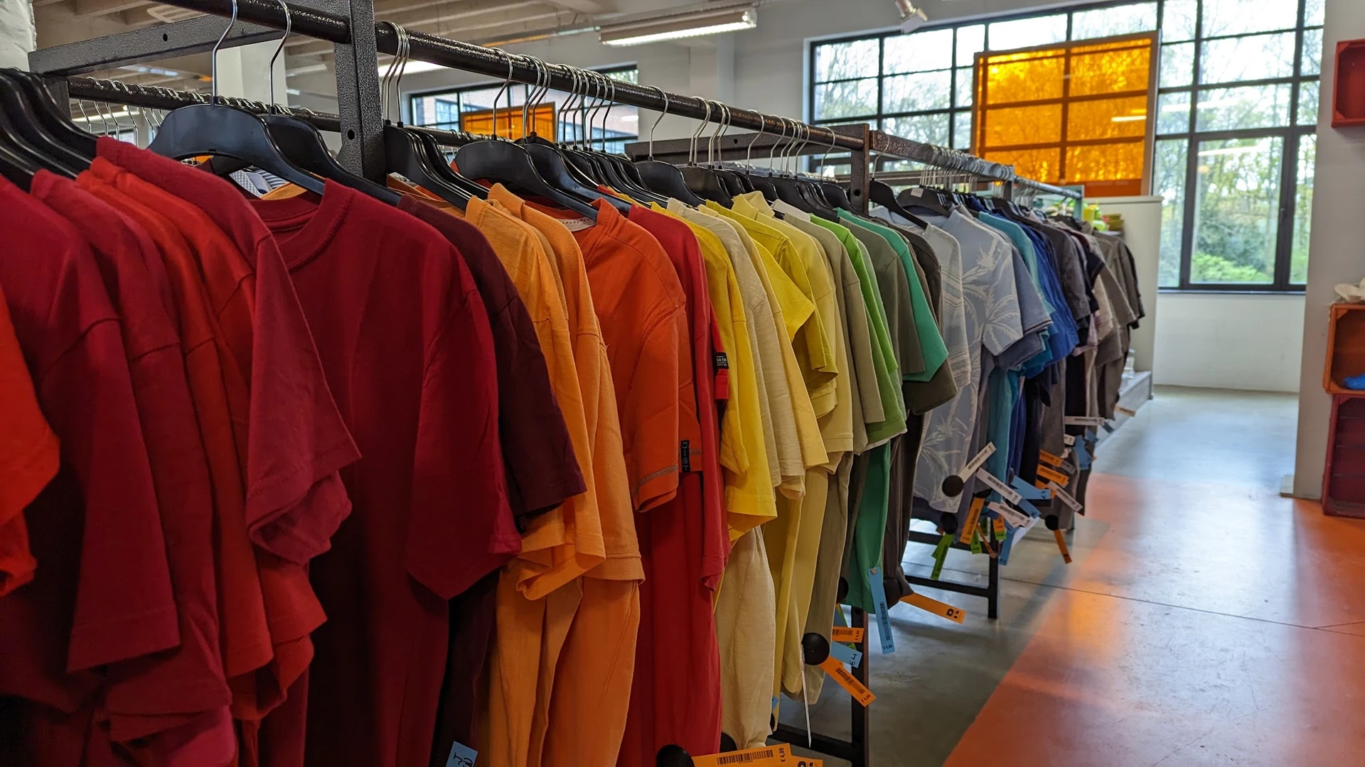 Rekken met kleurig gesorteerde tweedehands kleding in verschillende kleuren