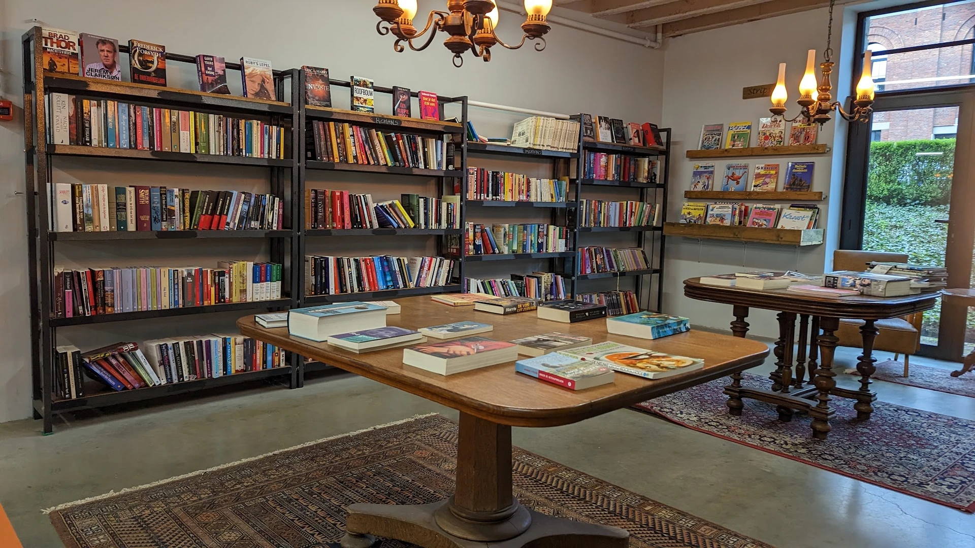 Boekenwinkel interieur met houten tafel vol boeken en zwarte boekenkasten langs de muren