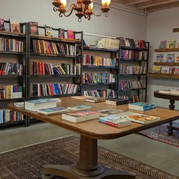 Boekenwinkel interieur met houten tafel vol boeken en zwarte boekenkasten langs de muren