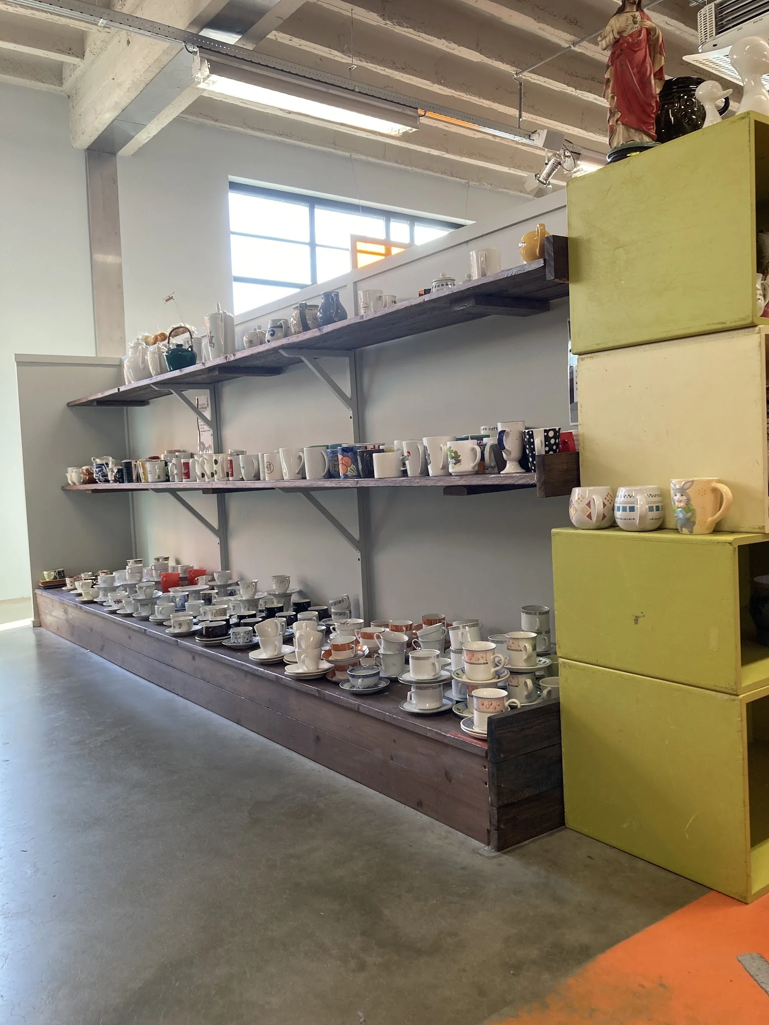 Wandplanken met servies, kannen, mokken en decoratieve items in een kringloopwinkel