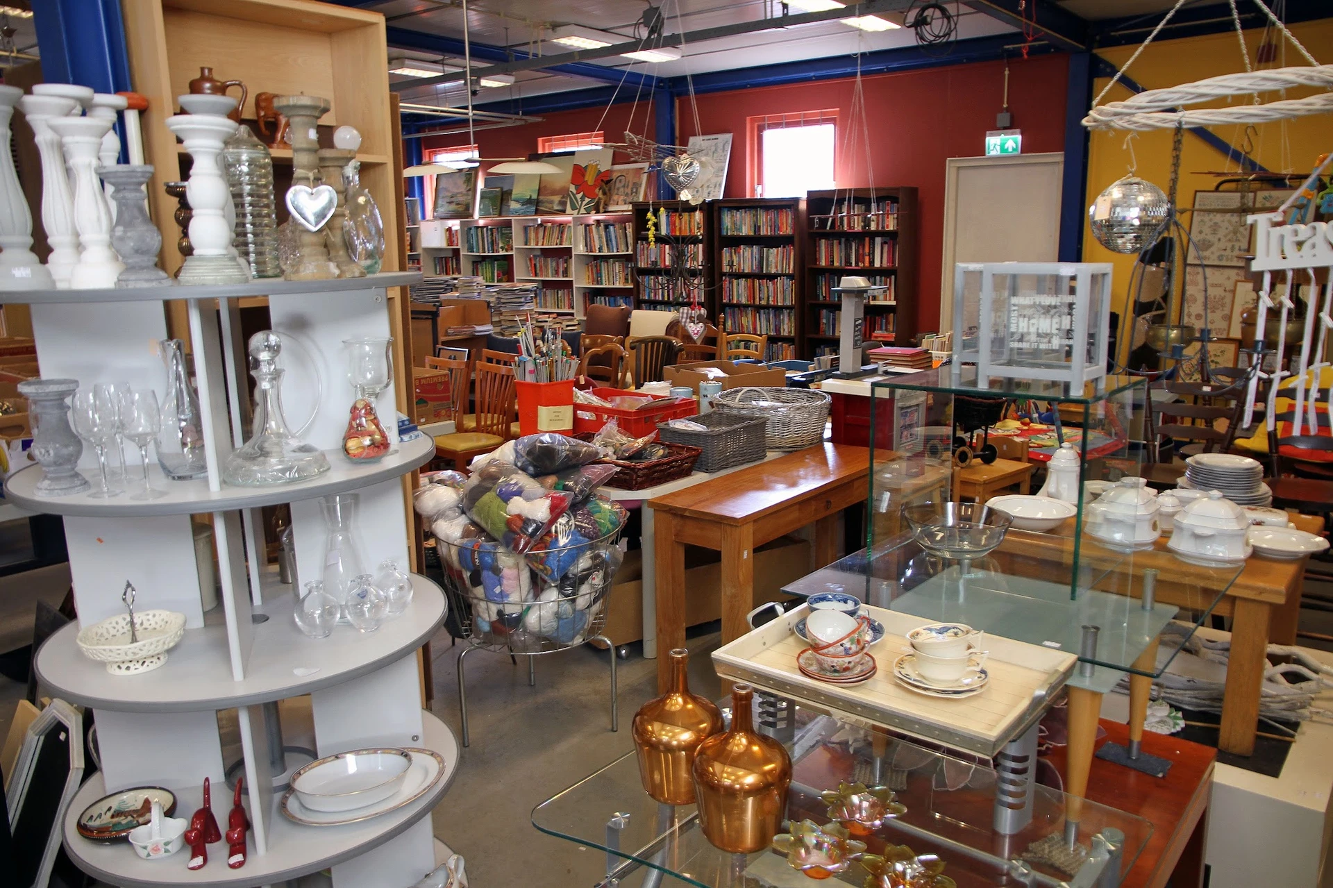 Winkelvloer met stellingen boeken, servies, glaswerk en diverse huishoudelijke artikelen uitgestald
