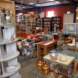 Winkelvloer met stellingen boeken, servies, glaswerk en diverse huishoudelijke artikelen uitgestald