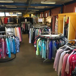 Overzicht van de winkelvloer met ronde rekken vol tweedehands kleding in verschillende kleuren