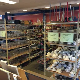 Stellingen met serviesgoed, kopjes, glazen en aardewerk in een kringloopwinkel