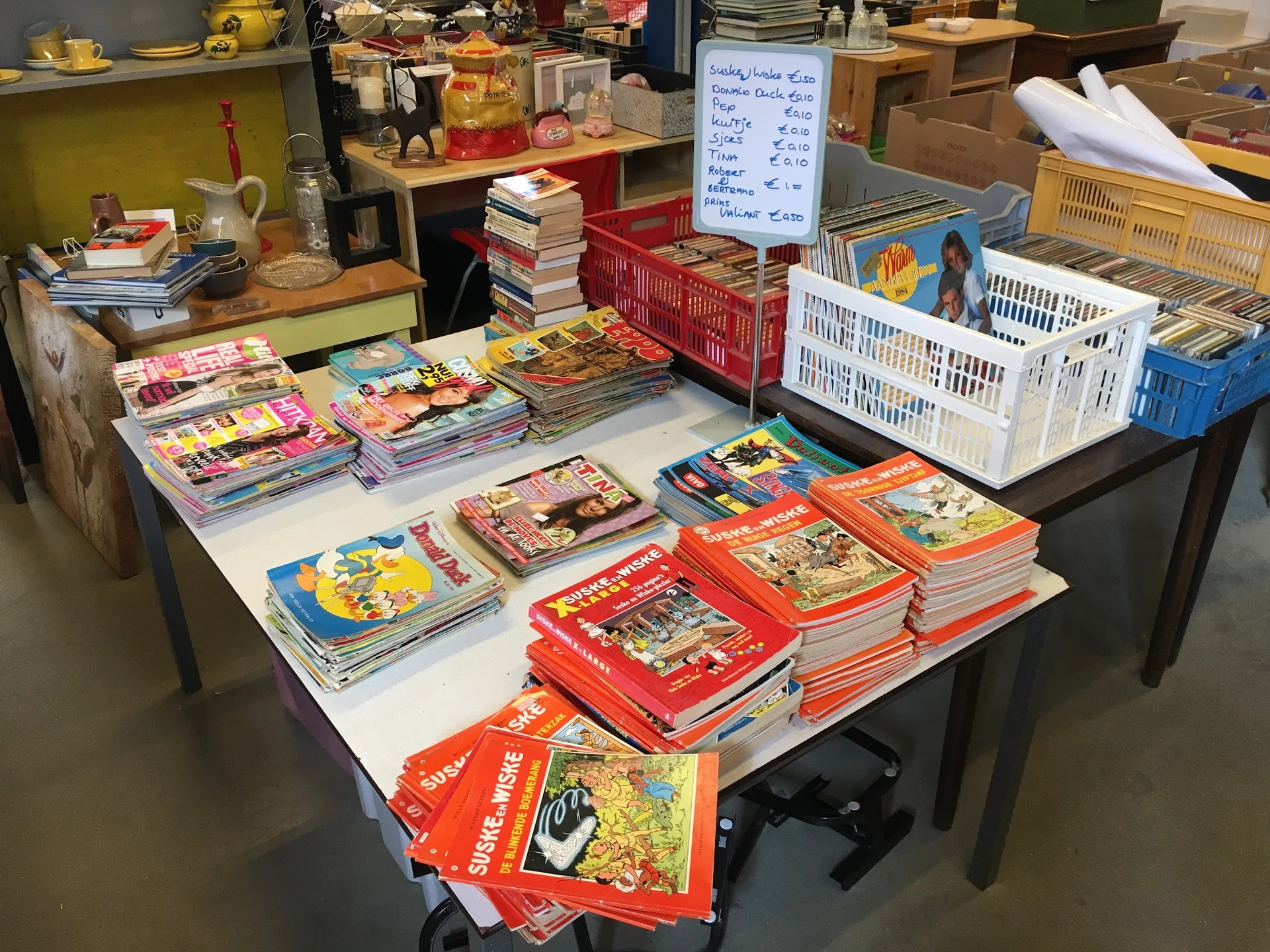 Tafel vol met gestapelde kinderboeken in verschillende kleuren en uitgaven