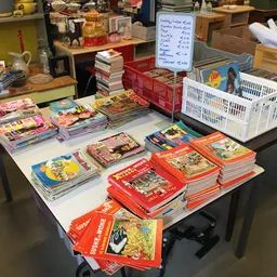 Tafel vol met gestapelde kinderboeken in verschillende kleuren en uitgaven