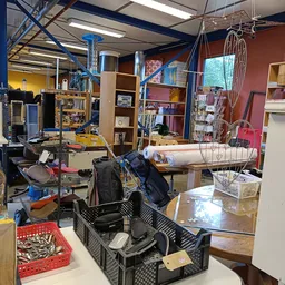 Winkelinterieur met stellingen, diverse spullen, werkstations en opbergtafels vol met tweedehandsartikelen