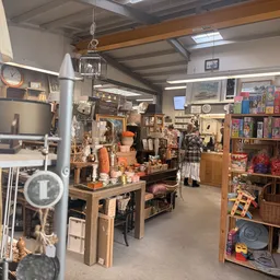 Winkelinterieur met werkbank, boekenrekken, vintage spullen en decoratieve artikelen in kringloopwinkel