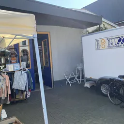 Winkelruimte met kledingrekken, fietsen en een bord met winkellogo tegen de muur