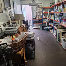 Winkelvloer van kringloopwinkel met stellingen, dozen, manden met spullen en diverse artikelen