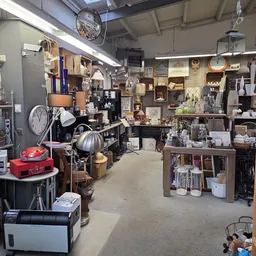 Winkelvloer van kringloopwinkel met diverse meubels, lampen, klokken en huishoudspullen uitgestald