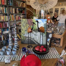 Interieur van kringloopwinkel met boekenkasten, display met vogels, kopjes, servies en decoratieve items op tafels