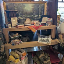 Houten bureau met boeken, decoratieartikelen en verschillende tweedehands spullen uitgestald