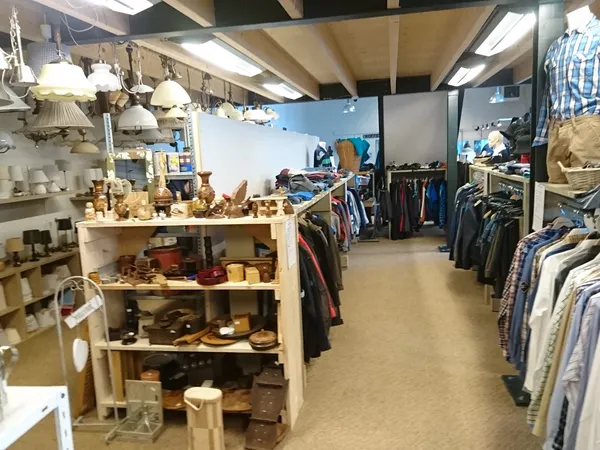 Winkelinterieur met kledingrekken en een houten display met huishoudelijke artikelen en decoratie