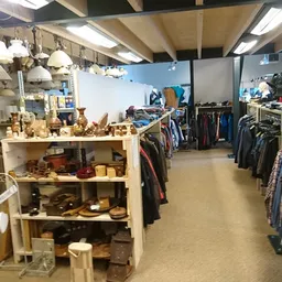 Winkelvloer met kledingrekken, houten display met huishoudartikelen en lampen aan het plafond