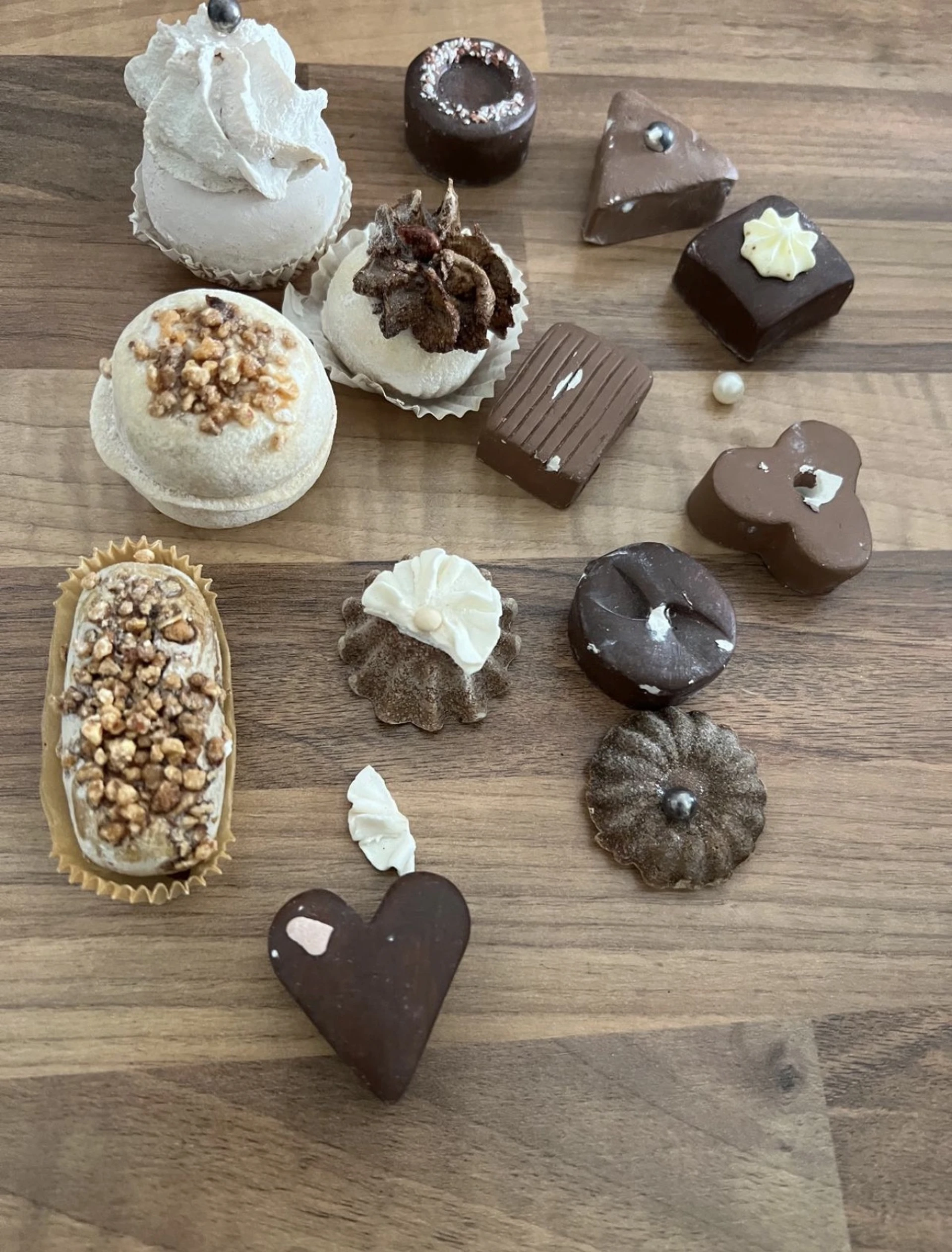 Assortiment chocoladetruffels en gebakjes op houten tafel, waaronder chocolade bonbons met witte topping en nougat-gevulde ta