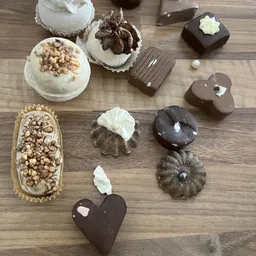 Assortiment chocoladetruffels en gebakjes op houten tafel, waaronder chocolade bonbons met witte topping en nougat-gevulde ta
