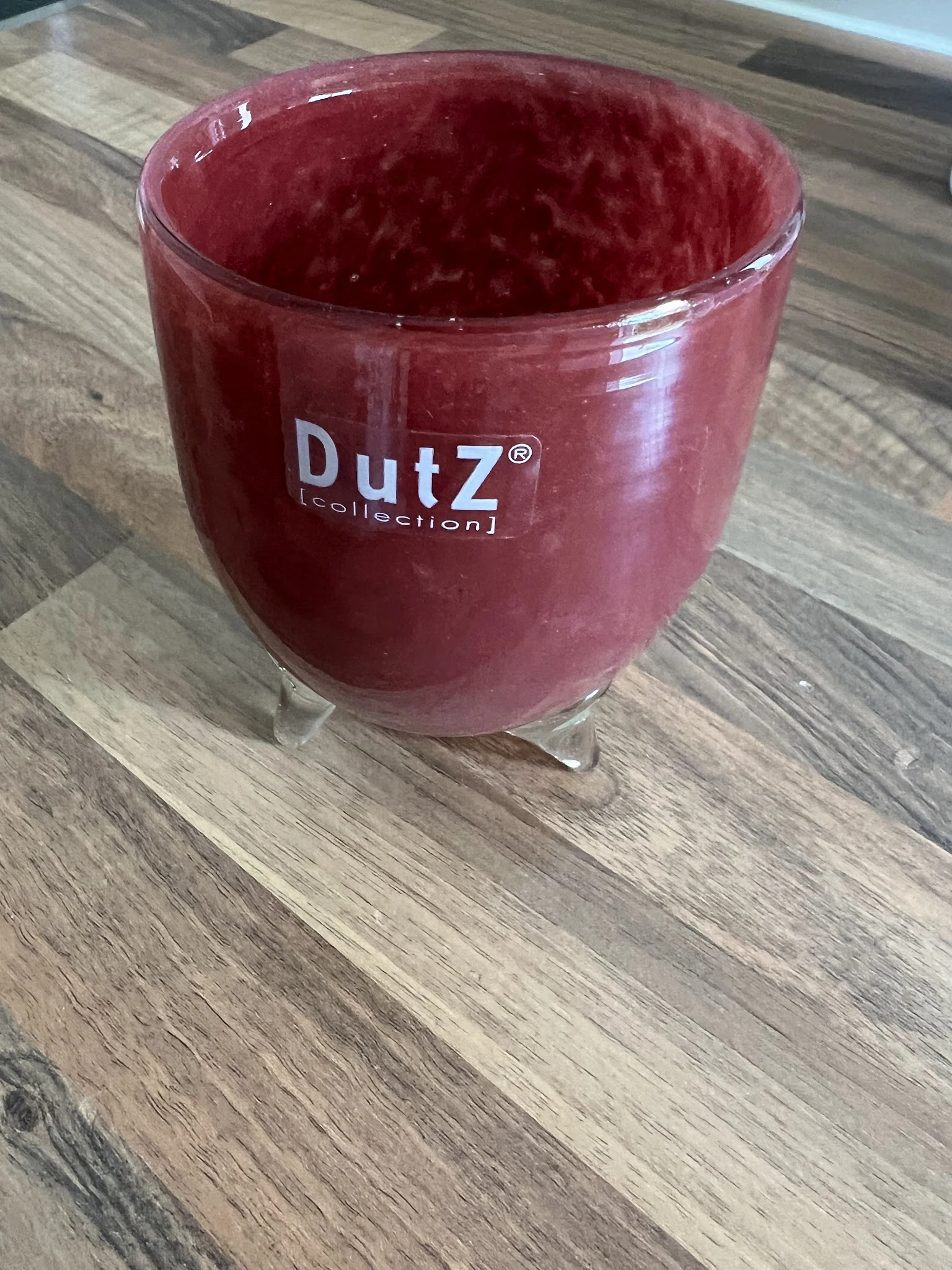 Rode glazen pot met DutZ-merk erop, op een houten ondergrond