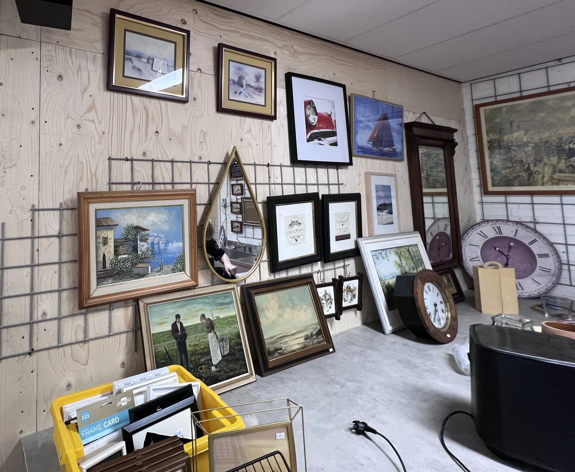 Uitgestalde tweedehands spullen: schilderijen, lijsten, klokken, decoratie en diversen items in de kringloopwinkel