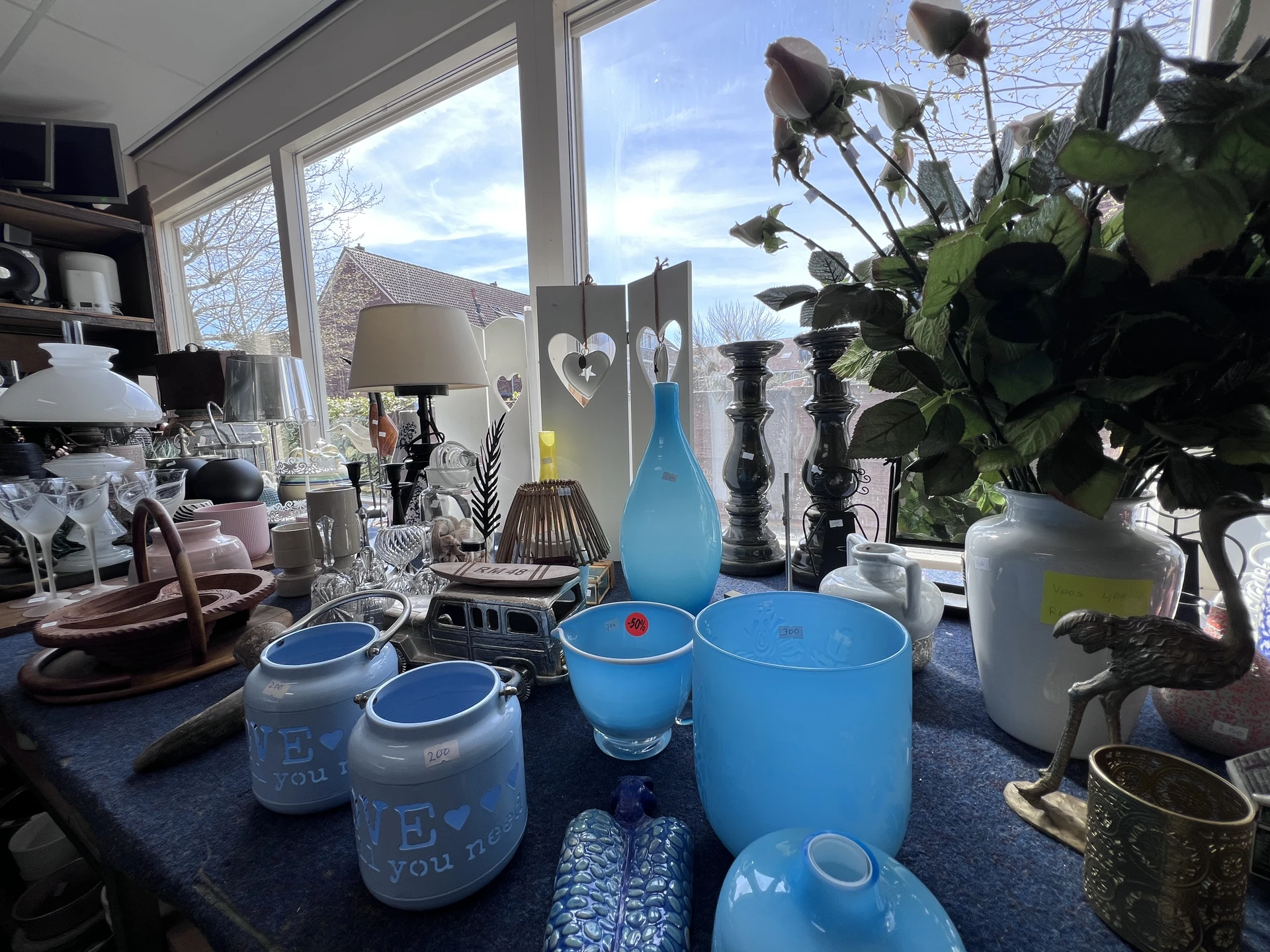 Blauwe serviesgoed en andere huishoudelijke spullen op een tafel bij raam