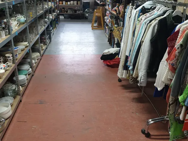 Winkelpad met aan linkerzijde schappen met huishoudartikelen en aan rechterzijde rekken met kleding