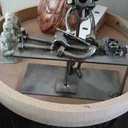 Close-up van een metalen werkbank of montagegereedschap met twee parallelle buizen en klemmen op een grijze basis