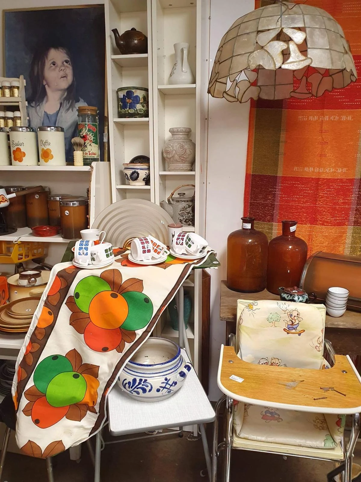 Uitgestalde serviesgoed, glazen en decoratieve items in een kringloopwinkel