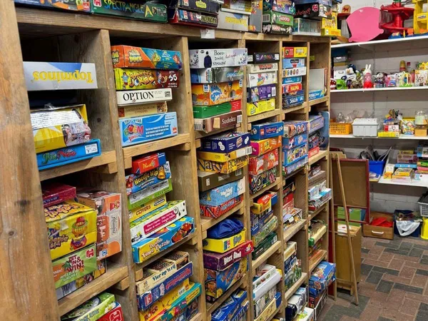 Houten stellingen volgestapeld met dozen spellen, bordspellen en speelgoed in diverse kleuren