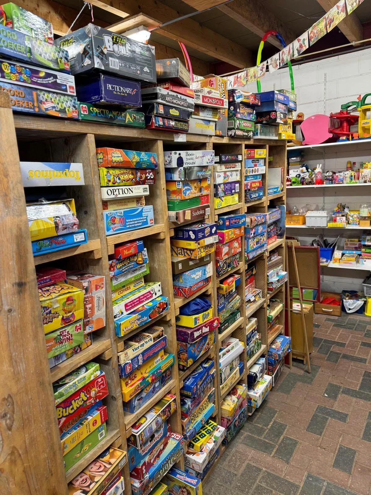Houten stellingen volgestapeld met dozen spellen, bordspellen en speelgoed in diverse kleuren