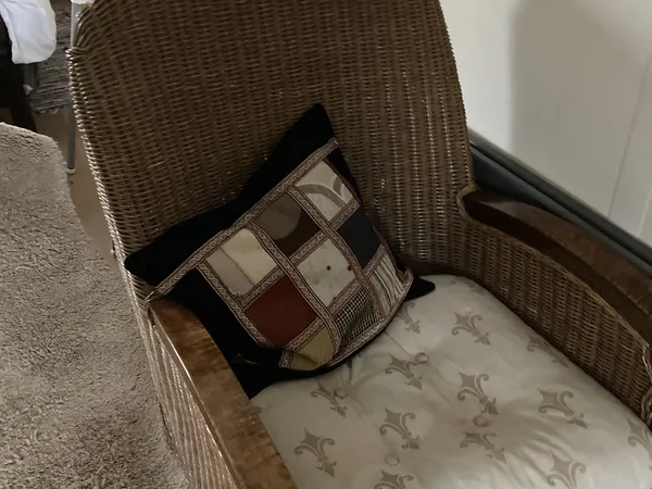 Rieten stoel met gekleurde patchwork kussen en gestreepte rug in tweedehands winkel