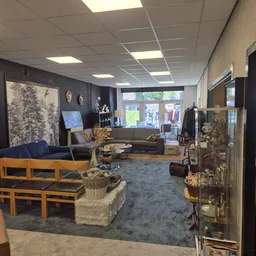 Winkelvloer met zithoeken, meubels, kunstwerken aan muren en vintage spullen op display