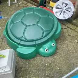 Groene kunststof schildpadzandkasteel met dekselvormige rug en twee ogen