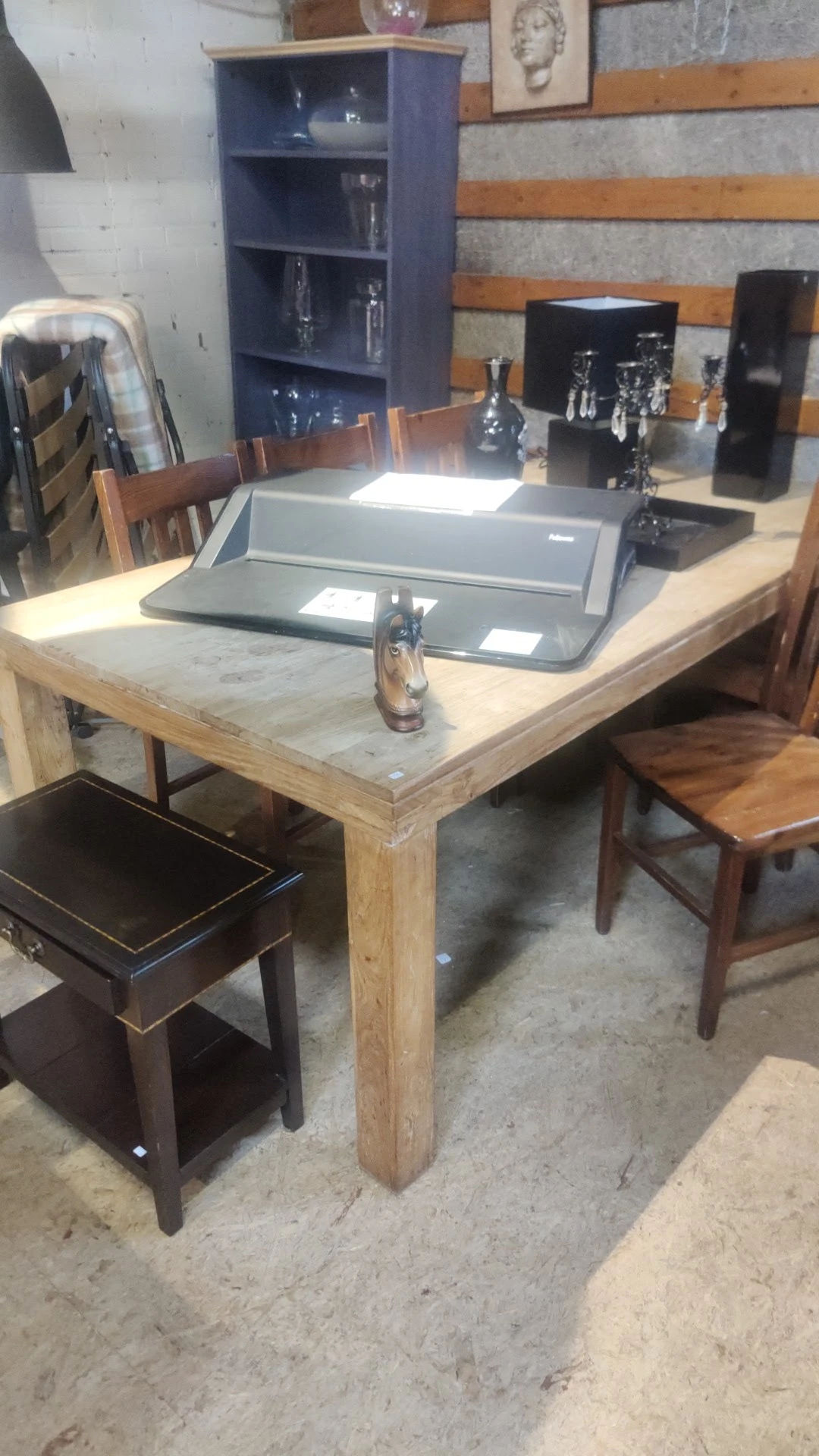 Houten tafel met marmeren blad en zwarte stoel in kringloopwinkel
