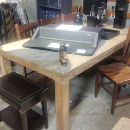 Houten tafel met marmeren blad en zwarte stoel in kringloopwinkel