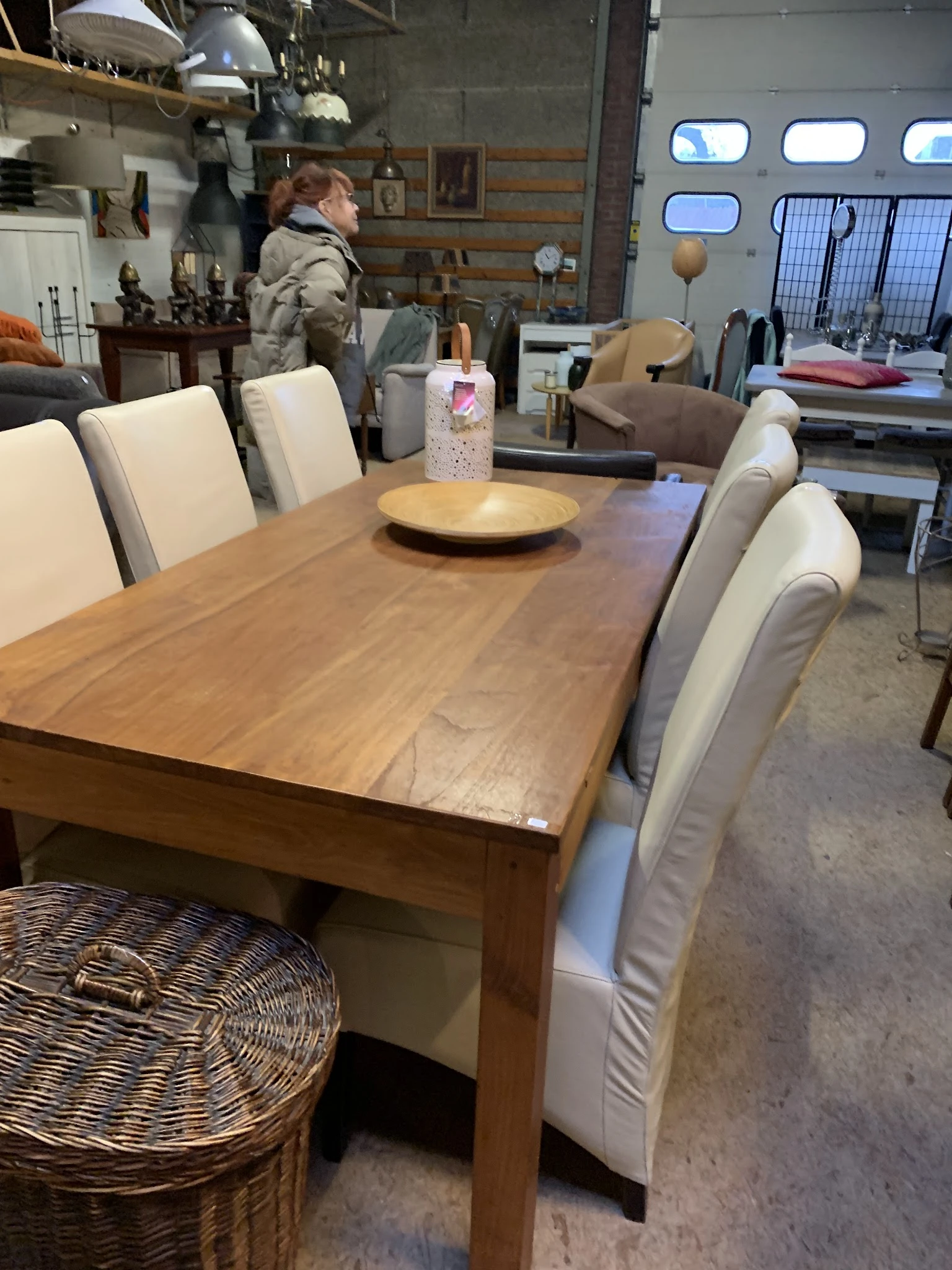 Houten eettafel met vier beige stoelen en decoratieve items in kringloopwinkel