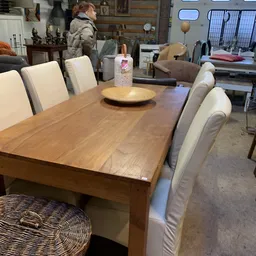 Houten eettafel met vier beige stoelen en decoratieve items in kringloopwinkel