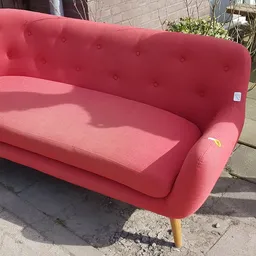 Roze/rood fauteuil met knopen en houten poten op een terras