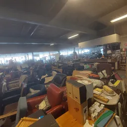 Overzicht van de winkelruimte met verschillende meubels, boeken en spullen uitgestald op tafels en in kasten
