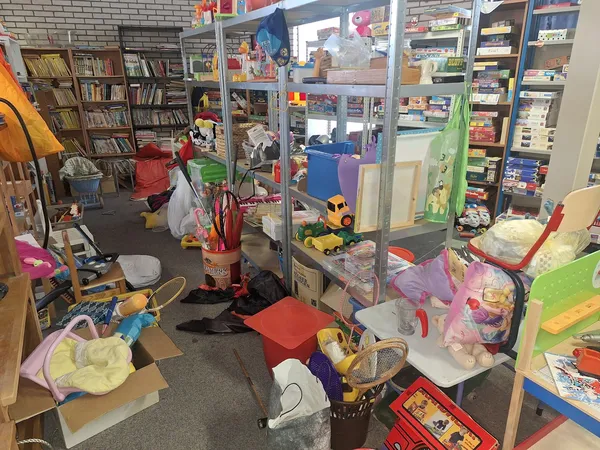 Rommelige winkelvloer met speelgoed, boeken en diverse spullen verspreid in de kringloopwinkel