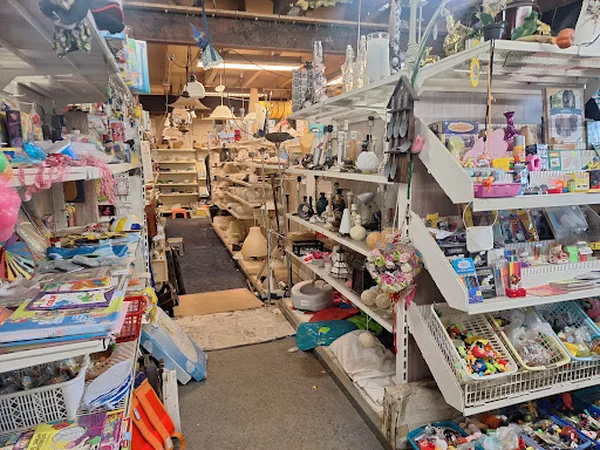 Binnenaanzicht van kringloopwinkel met rekken, stellingen en diverse spullen langs de wanden en gangpaden
