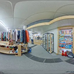 Overzicht van kringloopwinkel met kledingrekken, boekenkasten en diverse spullen uitgestald op de vloer