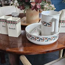 Ronde houten tafel met wit servies, bloemen in vaas en witte potten met etiketten