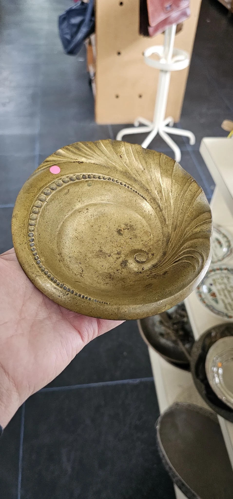 Goudkleurige decoratieve schaal met spiraal- en sierornamenten, in hand gehouden