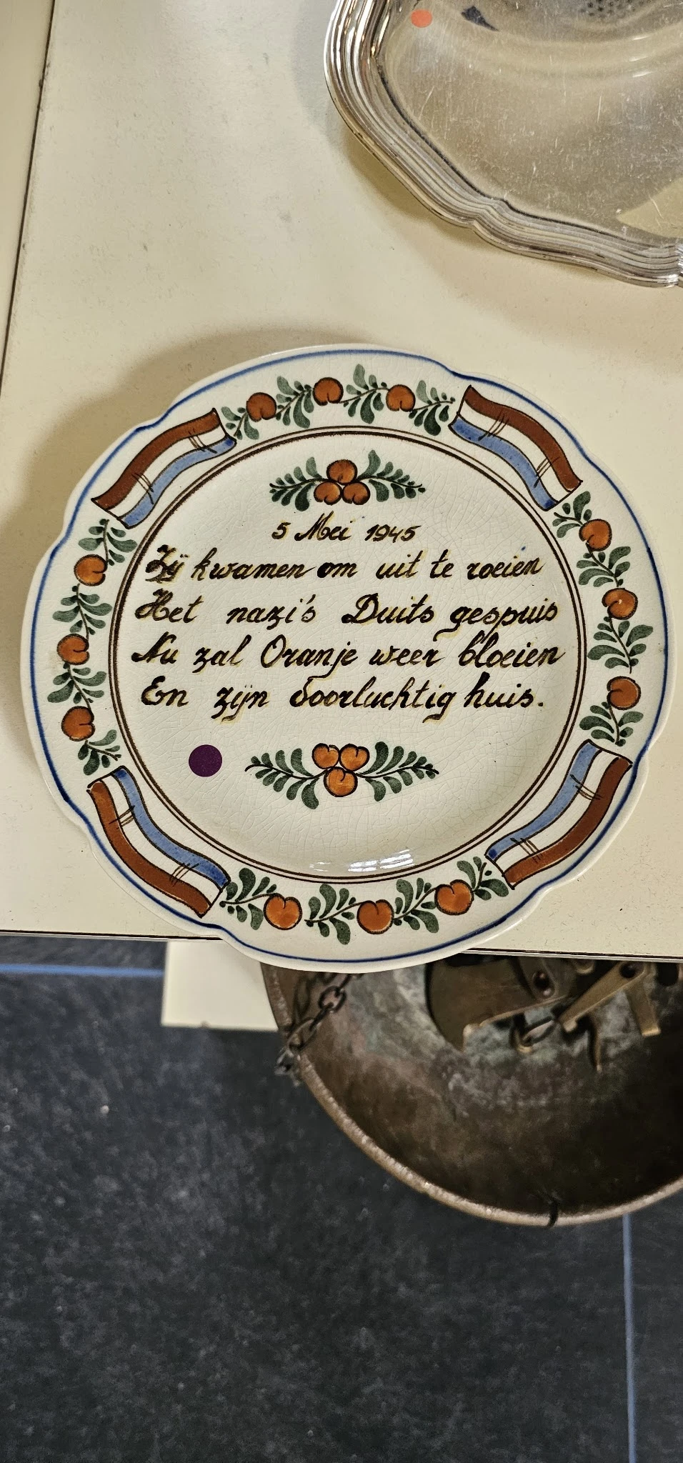 Decoratief aardewerk bord met Nederlands gedicht uit 1945 en siermotieven met oranje bloemen