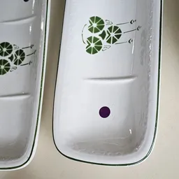 Twee witte serviesschalen met groen blad-patroon en een donkerpaarse stip