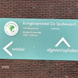 Turquoise bord aan bakstenen muur met openingstijden en routeaanwijzingen naar winkel en ophalen