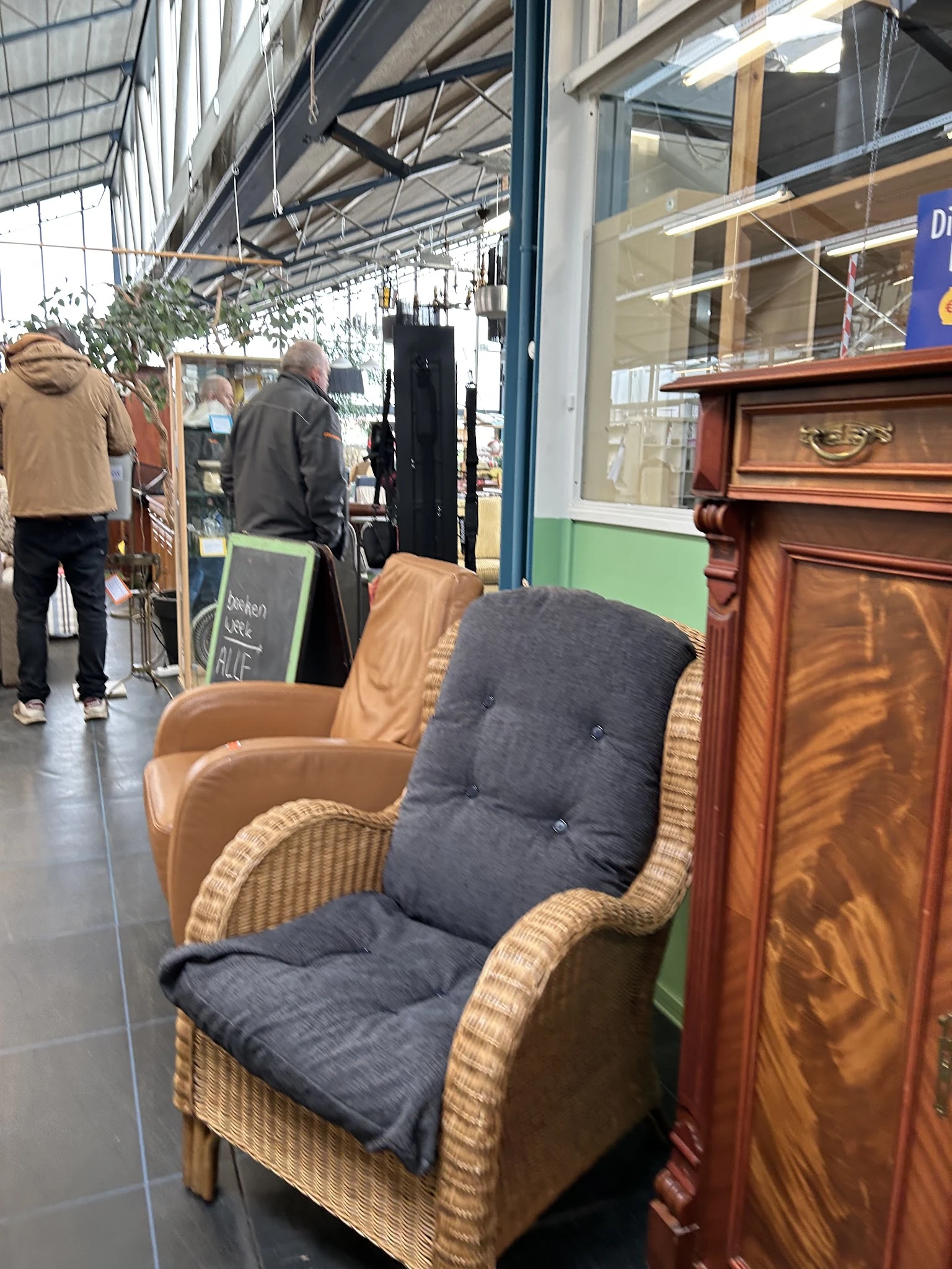 Fauteuils en meubels in de winkelruimte, waaronder een beige stoel en een donkerblauwe stoel met voetsteun
