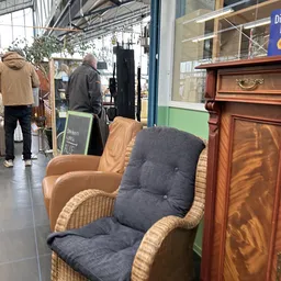 Fauteuils en meubels in de winkelruimte, waaronder een beige stoel en een donkerblauwe stoel met voetsteun